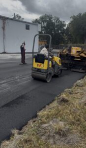 Paving crew rolling new asphalt parking lot